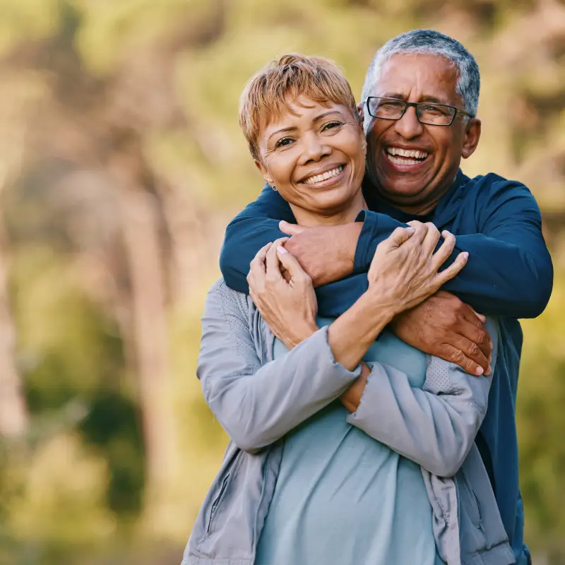 Nature, love and portrait of a senior couple hugging in a garden while on romantic outdoor date. Happy, smile and elderly people in retirement embracing in park while on a walk for fresh air together<br />
